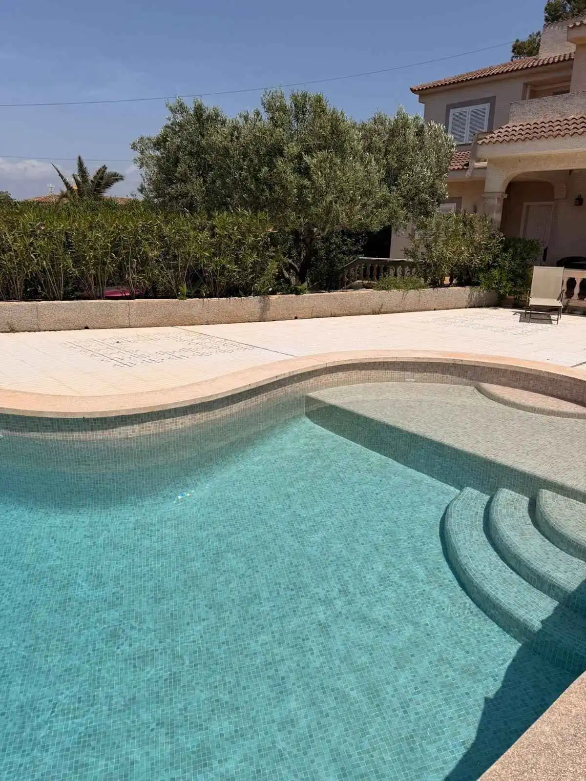 Piscina con gresite turquesa y escalera romana integrada en una vivienda de Mallorca