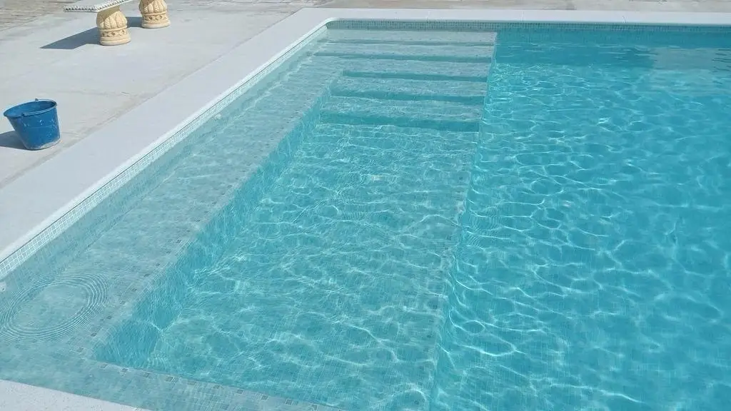 Piscina con escalera de obra integrada y revestimiento de gresite blanco en Mallorca