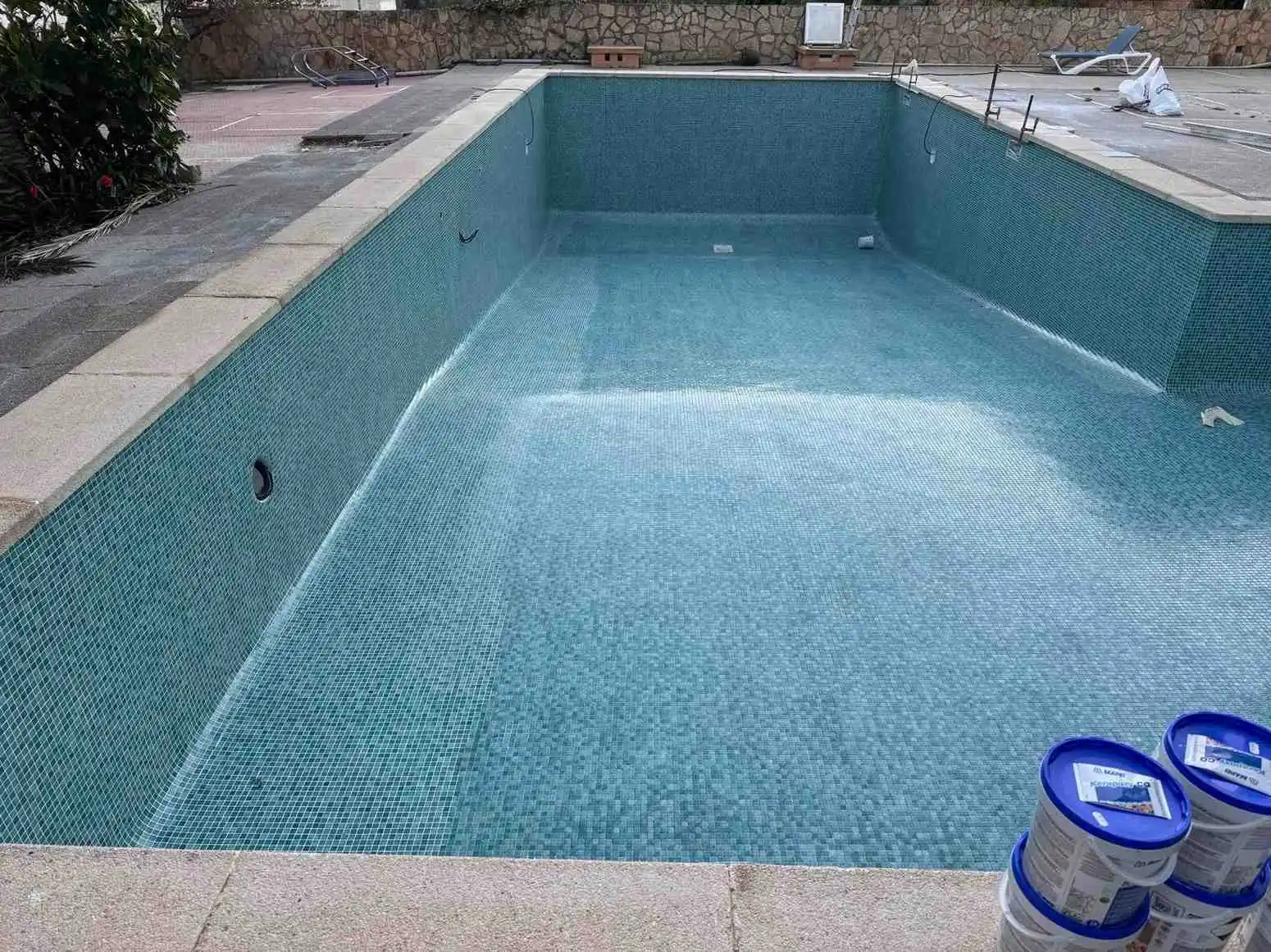 Piscina con revestimiento de gresite azul y escalera romana de obra con barandilla metálica en Mallorca