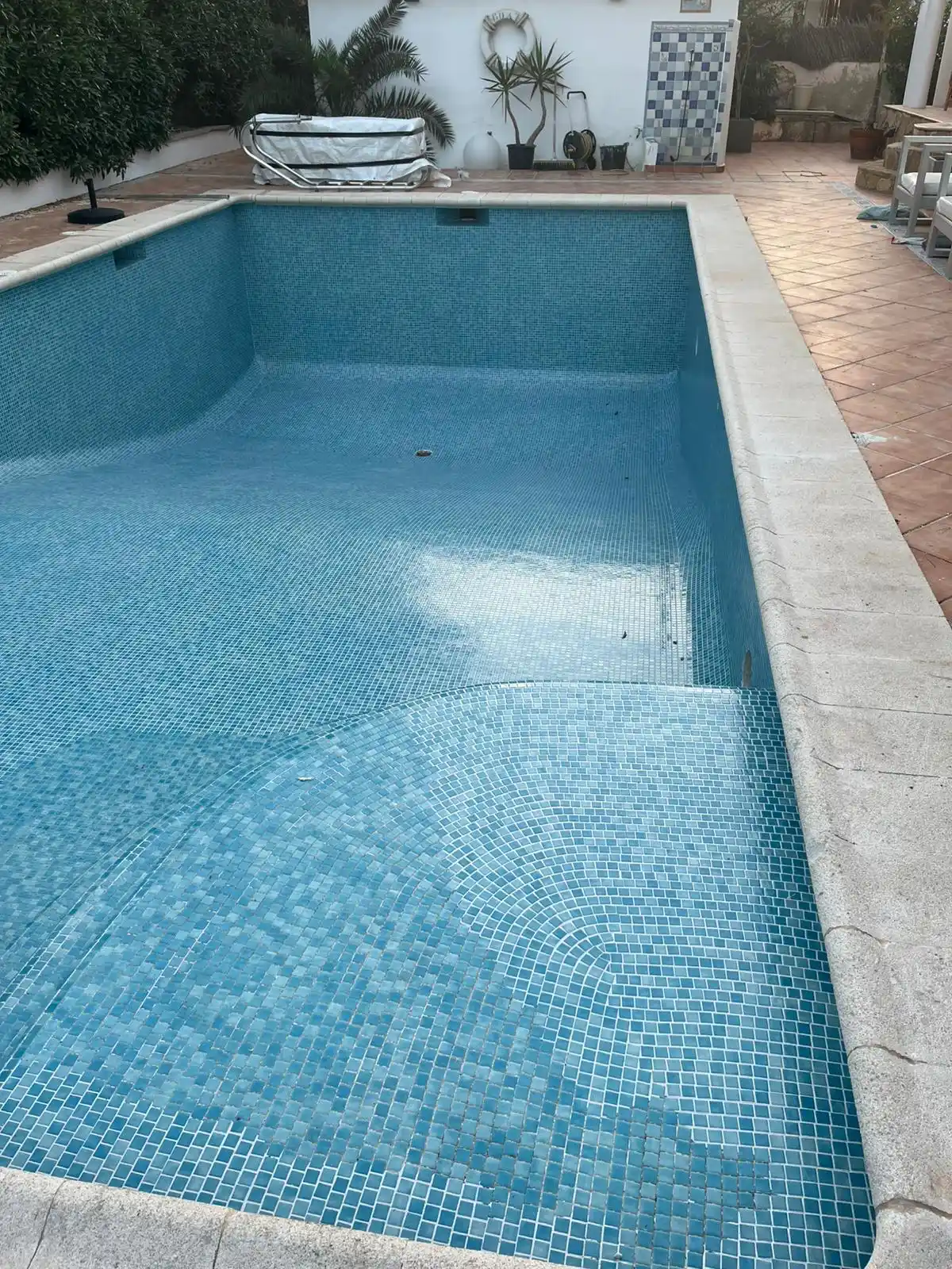 Piscina con revestimiento de gresite azul y borde de piedra clara en Palma