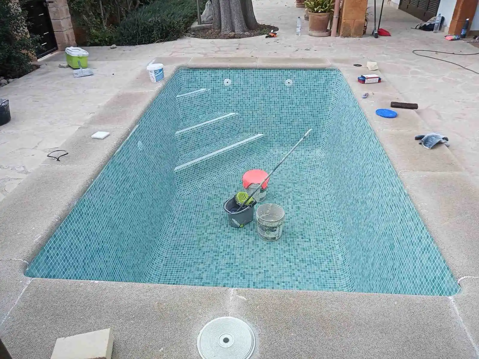 Piscina con escalera de obra integrada y revestimiento de gresite blanco en Mallorca