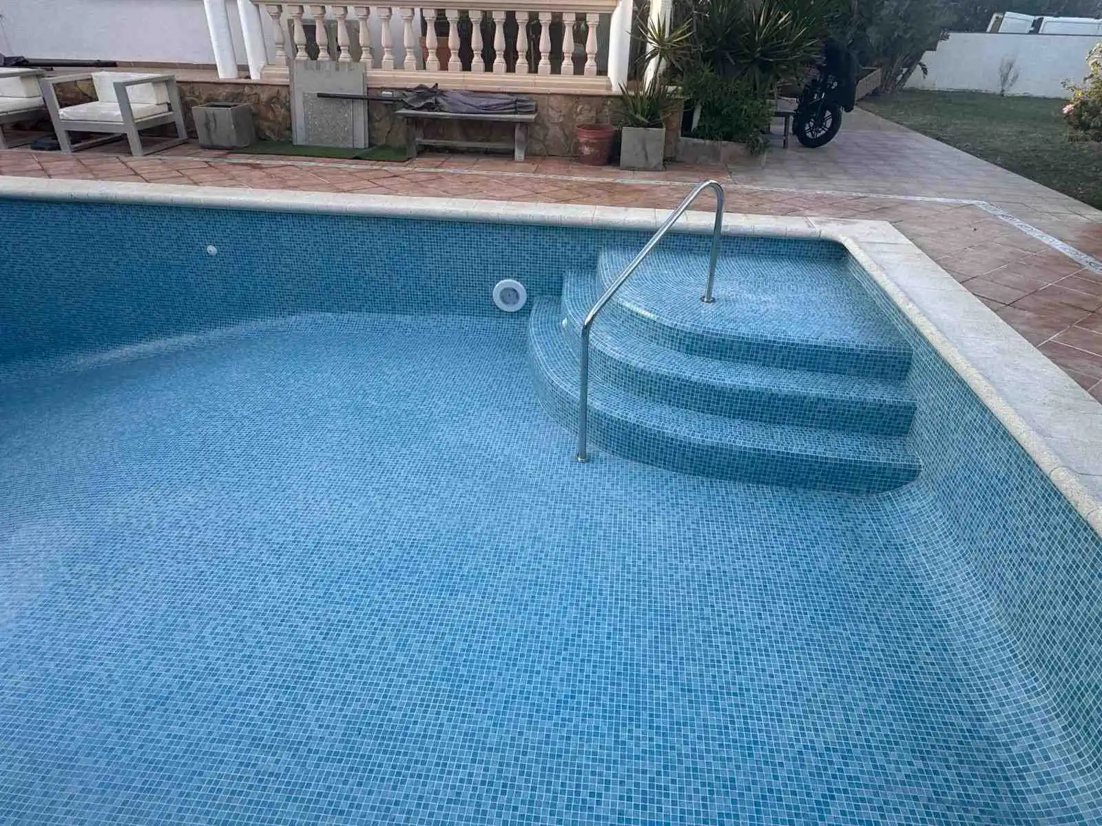 Piscina con escalera de obra integrada y revestimiento de gresite blanco en Mallorca