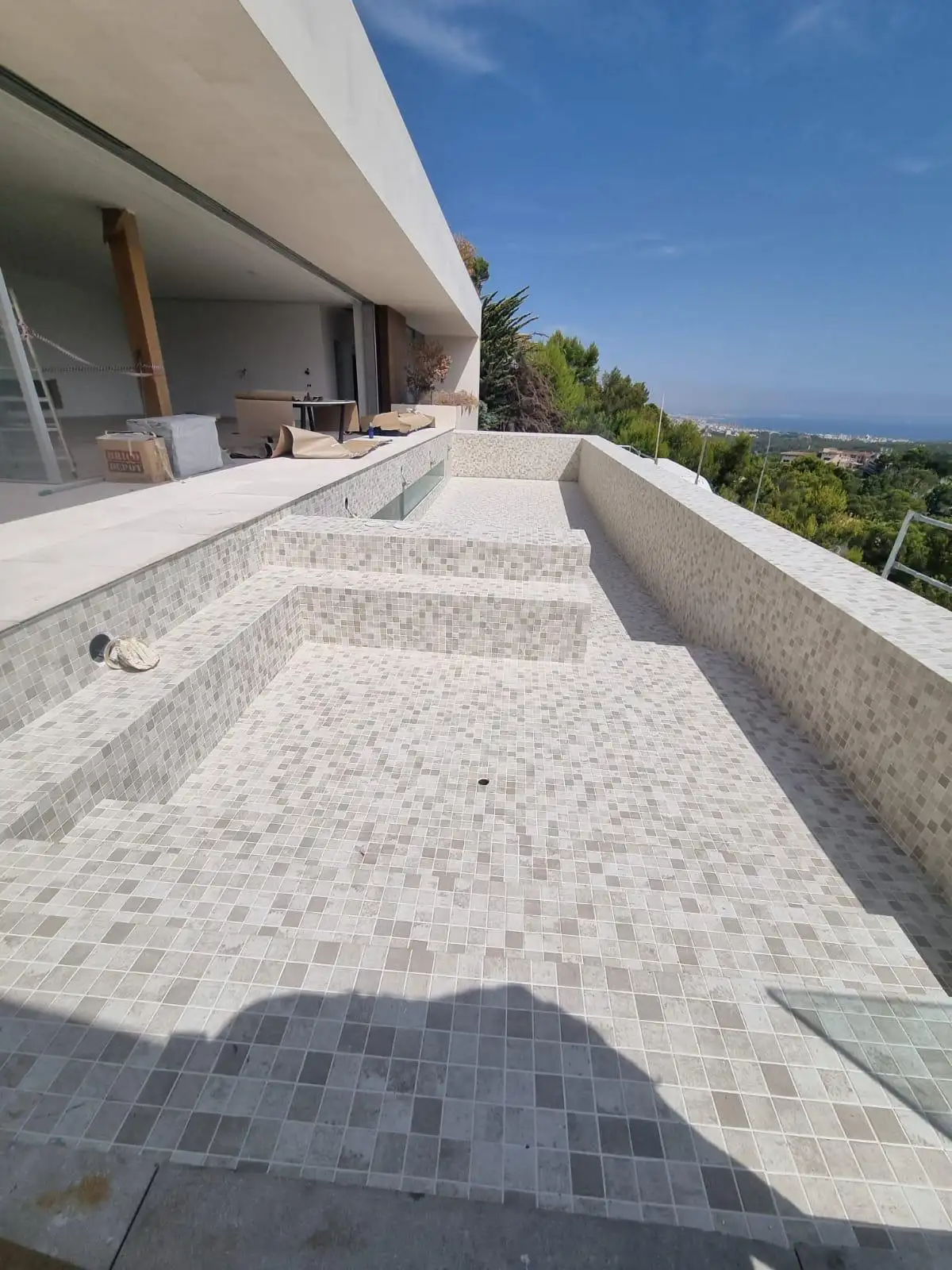 Construcción de piscina con revestimiento de gresite beige y escalones integrados en Palma