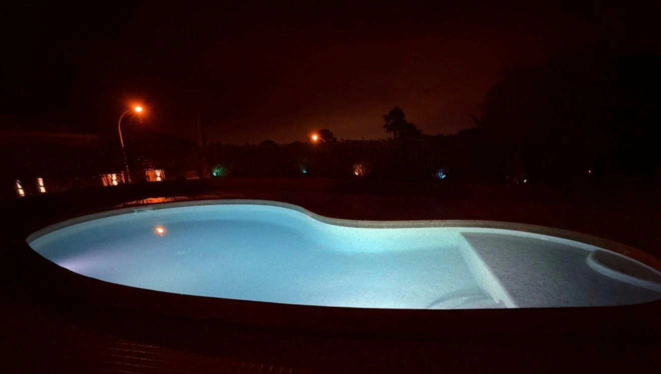 Piscina con iluminación led subacuática en tono azul y escalera de obra en Palma