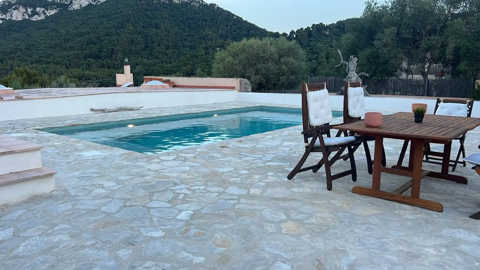 Piscina con revestimiento de piedra natural y zona de comedor exterior en Palma